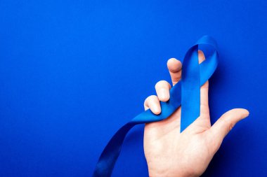 Prostat farkındalığı. Mavi kurdele, derin mavi arka planda izole edilmiş ellerde. Kasım ayında erkek sağlığının prostat kanseri olduğunun farkındalığı. Sağlık hizmetleri, Uluslararası erkekler, Babalar Günü