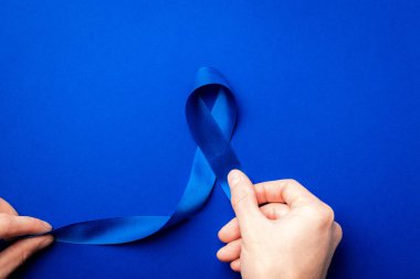 Prostat bakımı. Kasım ayında erkek sağlığının prostat kanseri olduğunun farkındalığı. Mavi kurdele, derin mavi arka planda izole edilmiş ellerde. Dünya Kanser Günü ve Dünya Diyabet Günü Konsepti