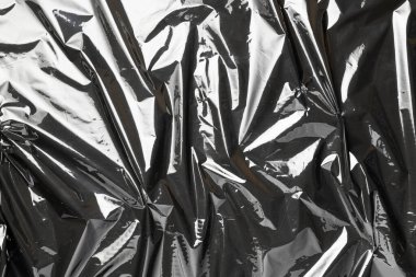 Plastik doku arka planı. Şeffaf koyu selofanı sar. Selofan siyah parlak film çantası deseni. Yaratıcı buruşuk arkaplan