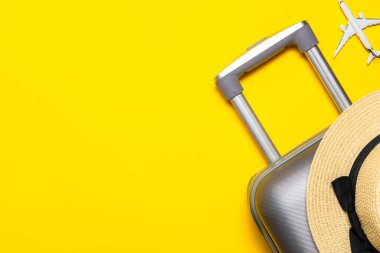 Yaz arkaplan masası. Çanta, palmiye yaprakları ve hasır şapkalı güneş gözlüğü, sarı arka planda seyahat kompozisyonu olan beyaz bir uçak. Kopyalama alanı, yaz tatili ve iş seyahati kavramı