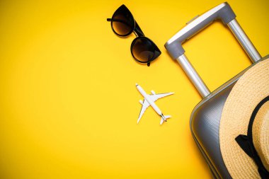 Yaz zamanı. Çantalı seyahat aksesuarları, beyaz bir uçak, sarı arka planda minimum tatil konsepti olan palmiye yaprakları. Kopya alanı olan egzotik tropikal plaj