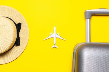 Deniz arka planı. Çantalı seyahat aksesuarları, beyaz bir uçak, sarı arka planda minimum tatil konsepti olan palmiye yaprakları. Kopyalama alanı olan sakin sahil sahnesi