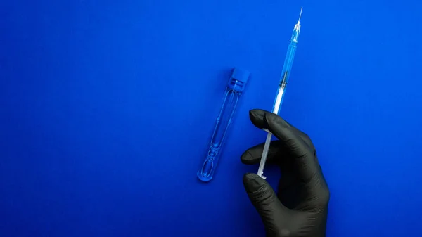 シリンジは孤立した 医療用手袋の医師の手は インフルエンザウイルスやコロナウイルスを保護するための針で注射器を保持します 青色で単離されたワクチン ウイルス対策の概念戦い Covid — ストック写真