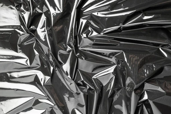 Plastic texture. Wrap transparent dark cellophane background. Black shiny film bag pattern. Real texture of polyethylene foil