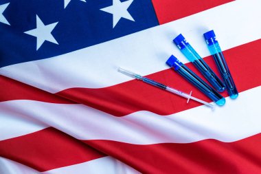 Aşı şişesi. Grip virüsünü ve koronavirüsü korumak için iğneli tıbbi şırınga. Amerika bayrağının kapak aşısı. İğneli tıbbi plastik aşı ekipmanları