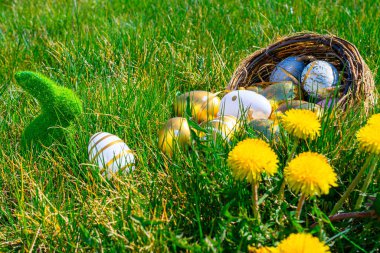 Paskalya yumurtaları. Sarı bahar çiçekli altın yumurta yeşil çimen arka planda kutlama sepetinde. Paskalya avı konsepti