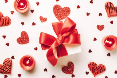 Mutlu günler. Kırmızı aşk kalpleri, romantik hediye kutusu, beyaz masada sevgililer günü mumu. Kopya alanı ile romantik mesaj şablonu. Üst Manzara. Yukarıdan görüntüle