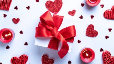 Aziz Valentin geçmişi: kırmızı aşk kalpleri, romantik hediye kutusu, beyaz masada mum. Kopya alanı ile romantik mesaj şablonu. Üst Manzara. Yukarıdan görüntüle