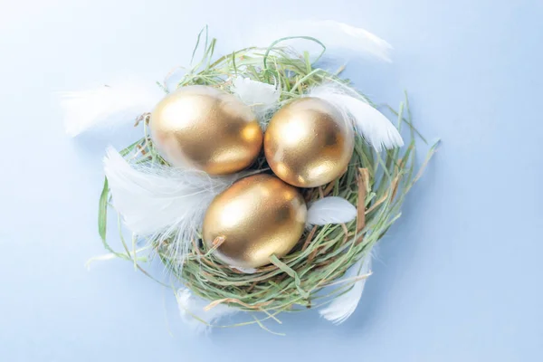 Πασχαλινά Αυγά Χρυσαφί Χρώμα Καλάθι Λευκά Φτερά Παστέλ Μπλε Φόντο — Φωτογραφία Αρχείου