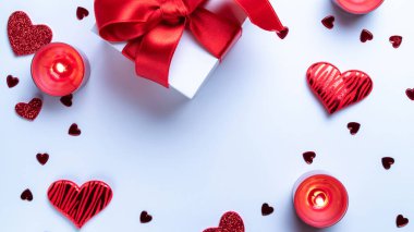 Mutlu günler. Kırmızı aşk kalpleri, romantik hediye kutusu, beyaz masada sevgililer günü mumu. Kopya alanı ile romantik mesaj şablonu. Üst Manzara. Yukarıdan görüntüle