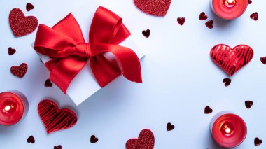 Sevgililer Günü kompozisyonu: kırmızı aşk kalpleri, romantik hediye kutusu, beyaz arka planda mum. Şubat aşkı hediye kartı. Üst Manzara. Yukarıdan görüntüle