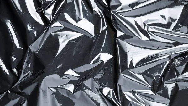 Pürüzsüz plastik doku. Siyah, parlak bir çanta deseni. Ambalaj ve ürün koruması için şeffaf koyu selofan arkaplanı sar