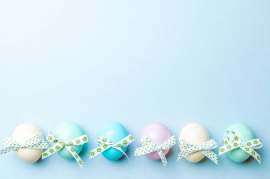 Paskalya lüksü. Mutlu Paskalya dekorasyonunda pastel mavisi arka planda bant şeritli renkli yumurta. Düz yatış, üst görünüm
