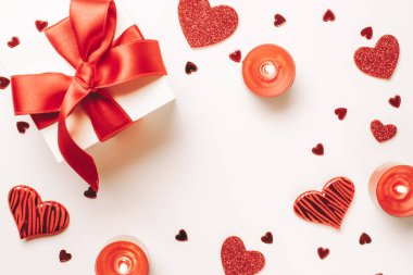 Sevgililer Günü kompozisyonu: kırmızı aşk kalpleri, romantik hediye kutusu, beyaz arka planda mum. Şubat aşkı hediye kartı. Üst Manzara. Yukarıdan görüntüle