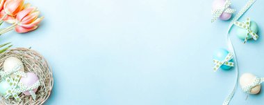 Bahar laleli altın Paskalya yumurtaları, Mutlu Paskalya dekorasyonunda pastel mavi arka planda beyaz tüyler. Bahar tatili afişi