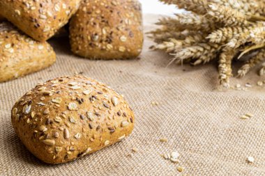 Baget ekmeği. Çavdar ekmeği ve ekmek kırıntılarıyla. Buğday tohumu kulaklı bir somun taze ekmek ya da doğal pamuk arka planında çivili bitki. Konsept - Evde Yemek Pişirme