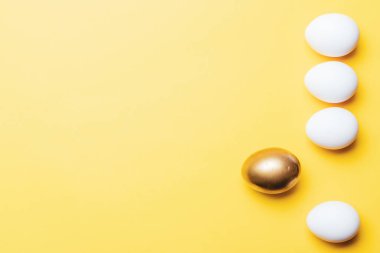 Paskalya süsü. Mutlu Paskalya dekorasyonunda pastel sarısı arka planda altın, beyaz renkli yumurta. Kopyalama alanı olan folyo minimalist yumurta tasarımı