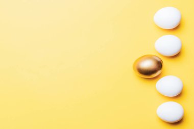 Paskalya yumurtaları. Mutlu Paskalya dekorasyonunda pastel sarısı arka planda altın, beyaz renkli yumurta. Folyo minimalist yumurta tasarımı, modern üst görünüm şablonu