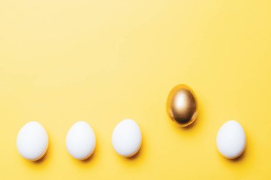 Paskalya yumurtaları izole. Mutlu Paskalya dekorasyonunda pastel sarısı arka planda altın, beyaz renkli yumurta. Düz yatış, üst görünüm
