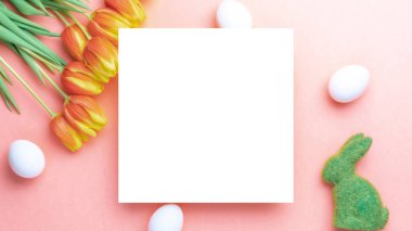 Paskalya kartı. Bahar laleleriyle sepetin içinde altın, beyaz yumurta, Mutlu Paskalya dekorasyonunda pastel pembe arka planda tüyler. Düz konum, kopyalama alanı olan üst görünüm