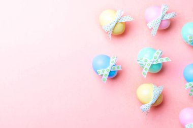 Paskalya süsü. Mutlu Paskalya dekorasyonunda pastel pembe arka planda bant şeritli renkli yumurta. Kopyalama alanı olan folyo minimalist yumurta tasarımı.