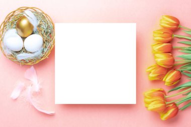 Paskalya yumurtası tavşanı. Bahar laleleriyle sepetin içinde altın, beyaz yumurta, Mutlu Paskalya dekorasyonunda pastel pembe arka planda tüyler. Düzlükte şenlik tasarımı.