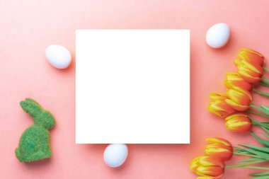 Paskalya sınırı. Bahar laleleriyle sepetin içinde altın, beyaz yumurta, Mutlu Paskalya dekorasyonunda pastel pembe arka planda tüyler. Düz yatış, üst görünüm