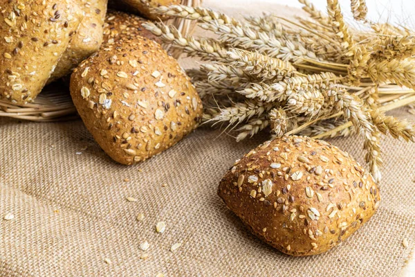 Baguette bread. Rye bakery with crusty loaves and crumbs. Fresh loaf of rustic traditional bread with wheat grain ear or spike plant on natural cotton background. Concept - Cooking at Home