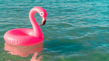 Tropikal arka plan. Mavi okyanus suyunda pembe şişirilebilir flamingo. Deniz yazı plajı arka planı için. Asgari yaz konsepti
