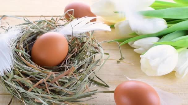 Farbige Eier Korb Mit Federtulpen Weiße Federn Auf Hölzernem Tischhintergrund — Stockvideo