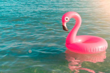 Yaz eğlencesi plajı. Yazın okyanus kıyısında mavi deniz suyunda şişme pembe flamingo. Çocuklar için komik bir oyuncak.