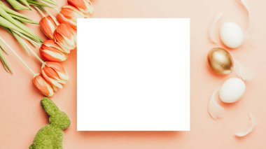 Paskalya yumurtası sepeti. Bahar laleli altın yumurta sepette, pastel pembe arka planda beyaz tüyler Mutlu Paskalya süslemesinde. Geleneksel güneş ışığı dekorasyonu. Üst görünüm