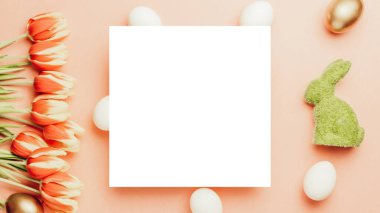 Paskalya yumurtaları. Bahar laleleriyle sepetin içinde altın, beyaz yumurta, Mutlu Paskalya dekorasyonunda pastel pembe arka planda tüyler. Folyo minimalist yumurta tasarımı, modern üst görünüm şablonu