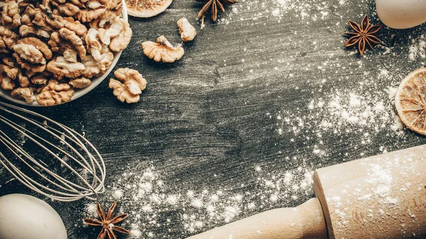 Bakery background. Cooking food ingredients: flour, eggs, nut and star anise, orange on dark table kitchen background for cake. Kitchen Food Frame