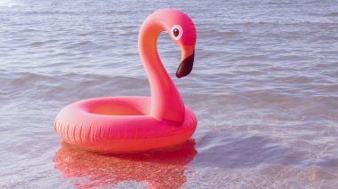 Merhaba yaz. Mavi okyanus suyunda pembe şişirilebilir flamingo. Deniz yazı plajı arka planı için. Moda yaz konsepti