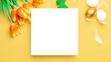 Paskalya yumurtaları izole. Bahar laleli altın, beyaz yumurta sepeti, Mutlu Paskalya dekorasyonunda pastel sarısı arka planda beyaz tüyler. Düz yatış, üst görünüm