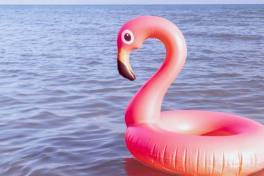 Merhaba yaz. Mavi okyanus suyunda pembe şişirilebilir flamingo. Deniz yazı plajı arka planı için. Moda yaz konsepti