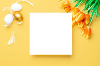 Paskalya yumurtası avı. Bahar laleleriyle sepetin içinde altın, beyaz yumurta, Mutlu Paskalya dekorasyonunda pastel sarısı arka planda tüyler. Üst görünümde geleneksel tasarım