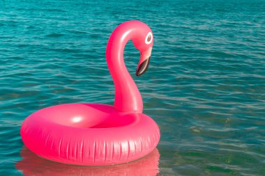 Flamingo ikonu. Yazın okyanus kıyısında mavi deniz suyunda şişme pembe flamingo. Moda yaz konsepti