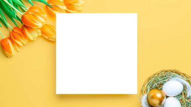 Paskalya bayrağı. Bahar laleleriyle sepetin içinde altın, beyaz yumurta, Mutlu Paskalya dekorasyonunda pastel sarısı arka planda tüyler. Folyo minimalist yumurta tasarımı, modern üst görünüm şablonu
