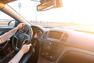 Gün batımında arabanın içinde mutlu bir sürücü. Genç bir kadın kış güneşli bir günde yolculukta iyi yolculuklar. Tatil konsepti