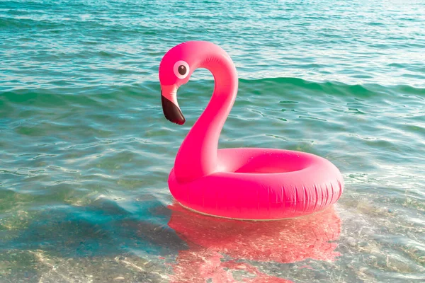 Sea background. Pink inflatable flamingo in blue ocean water for sea summer beach background. Luxury lifestyle travel