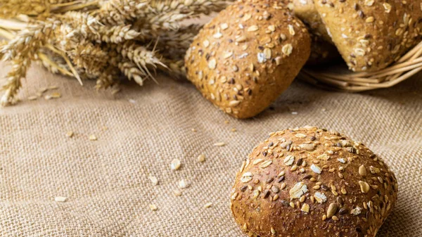 Traditional bread. Fresh loaf of rustic traditional bread with wheat grain ear or spike plant on linen texture background. Rye bakery with crusty loaves. Design element for bakery product label