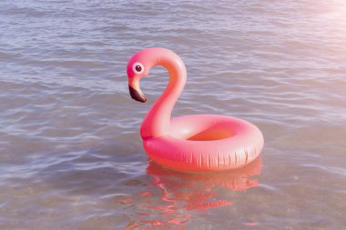 Merhaba yaz. Mavi okyanus suyunda pembe şişirilebilir flamingo. Deniz yazı plajı arka planı için. Moda yaz konsepti