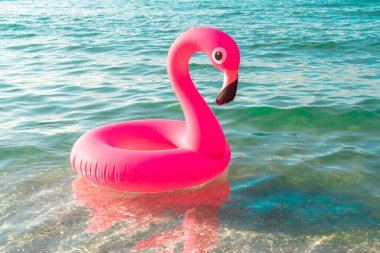 Yaz eğlencesi plajı. Yazın okyanus kıyısında mavi deniz suyunda şişme pembe flamingo. Çocuklar için komik bir oyuncak.
