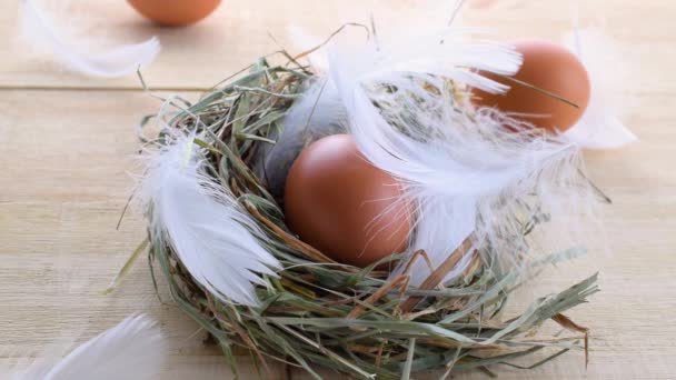 Яйца в корзине с весенними тюльпанами, белые перья на деревянном фоне стола в праздничном оформлении Пасхи. Миниатюрный дизайн яйца из фольги, современный вид сверху. — стоковое видео
