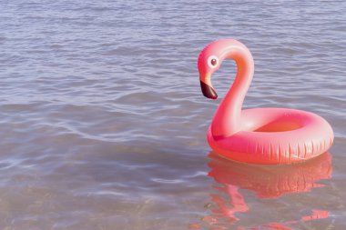 Merhaba yaz. Mavi okyanus suyunda pembe şişirilebilir flamingo. Deniz yazı plajı arka planı için. Moda yaz konsepti.