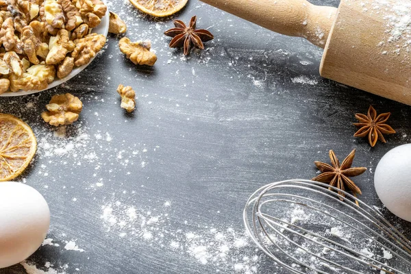 Bakery composition. Cooking food ingredients: flour, eggs, nut and star anise, orange on dark table kitchen background for cake. Top View Copy Space. Cookies Pie Or Cake Recipe Mockup.