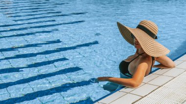Yaz eğlencesi. Bikini mayo, güneş gözlüğü ve mavi havuz suyunda dinlenen hasır şapkalı mutlu seksi kız. Kaplıca ve güneşlenme açık havada