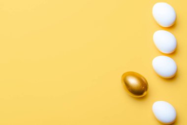 Paskalya süsü. Mutlu Paskalya dekorasyonunda pastel sarısı arka planda altın, beyaz renkli yumurta. Kopyalama alanı olan folyo minimalist yumurta tasarımı